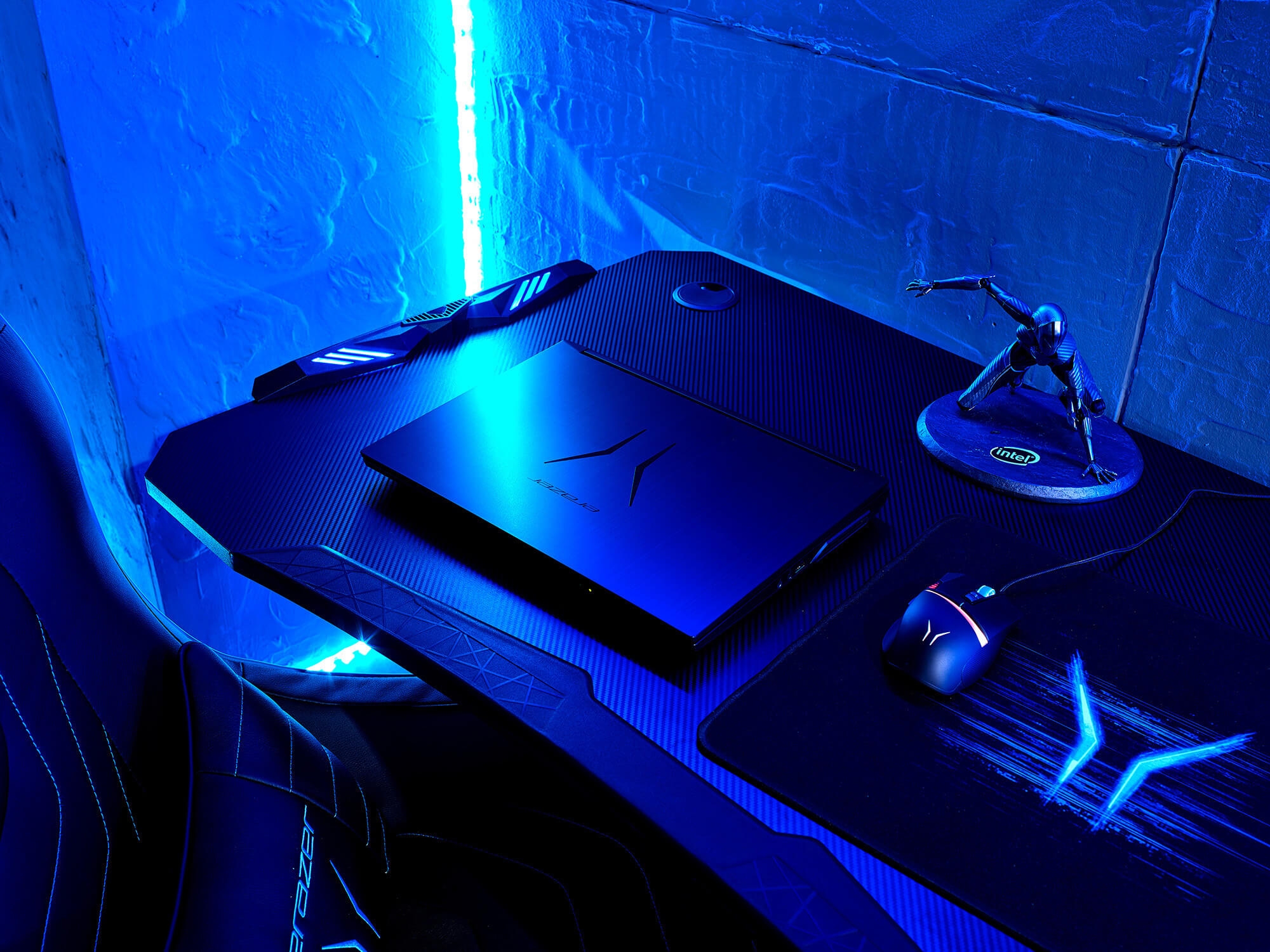 Ein ERAZER-Laptop auf einem Schreibtisch mit Gaming-Peripherie und blauem Neonlicht